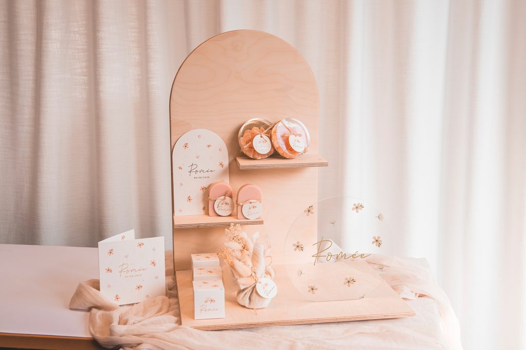 Geboorteconcept, doopsuiker en bedankjes Romée uitgestald op houten display. Alles in roze thema met bloemen, ook het geboortekaartje. Inspiratie voor unieke en persoonlijke babycadeaus op jouw geboortelijst.